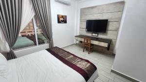 a bedroom with a bed and a desk with a television at Comfort Inn in Kampong Selayun
