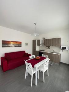sala de estar con sofá rojo, mesa y sillas en Villetta Azzurra, en Alcamo Marina