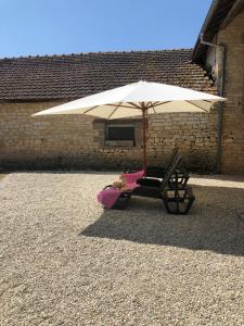 una silla bajo un paraguas sobre un suelo de grava en The charming private Farmhouse at La Grenouillére en Puyréaux