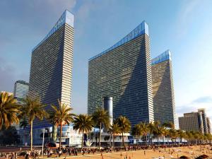 two tall buildings with palm trees in front of a city at Orbi City Inn in Batumi