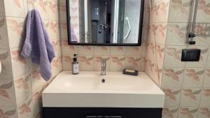 W łazience znajduje się umywalka z lustrem i fioletowy ręcznik. w obiekcie La casa sul porto w mieście Laveno-Mombello