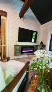 un soggiorno con TV, divano e fiori di Rustica Retreats Cottage a Middle Grove