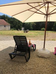 una sedia a dondolo nera sotto un ombrello per terra di The charming private Farmhouse at La Grenouillére a Puyréaux