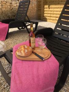 The charming private Farmhouse at La Grenouillére في Puyréaux: زجاجة من النبيذ وخبز على طاولة