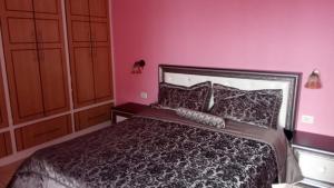 a bedroom with a bed and a pink wall at A&K Sea View Apartament 6 in Durrës