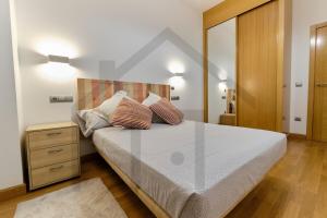 a bedroom with a large bed with two pillows on it at El pixin - Apartamento de gran categoría en GIJON in Gijón