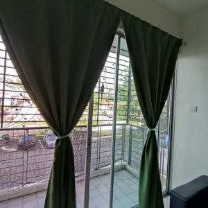 Duas cortinas verdes num quarto com janela em Homestay Nilai (Anggerik Court) em Nilai