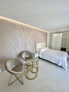 a bedroom with a bed and two chairs and a table at Sirena Suite Deluxe in Peschici