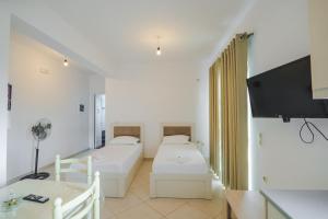 Zimmer mit 2 Betten, einem Tisch und einem TV in der Unterkunft Apartments Nano in Sarandë