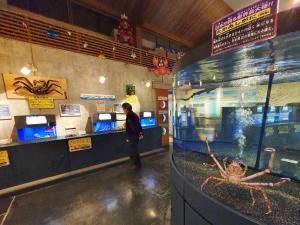 a man standing at a counter in a fish tank at Whole house rental 一棟貸切宿 "Your Home Tottori" 市内中心地近くの素敵な一軒家 in Tottori