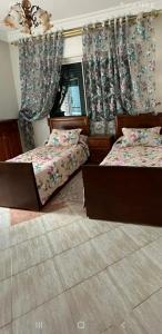 a bedroom with two beds and a window with curtains at Apartment soultana in Tangier