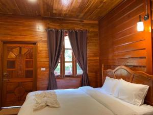 a bed in a wooden room with a window at Konglor Cave Resort in Ban O