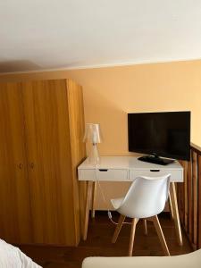 Schlafzimmer mit einem Schreibtisch, einem TV und einem weißen Stuhl in der Unterkunft CASA VACANZA TINDARA in Civitavecchia