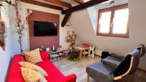 - un salon avec un canapé rouge et une télévision dans l'établissement GITE LE COQ ROUGE, à Eguisheim