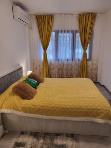 a bedroom with a large yellow bed with curtains at Apartament NECTARIA in Băile Herculane