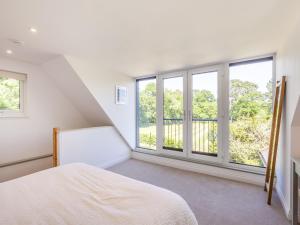 een slaapkamer met witte muren en grote ramen bij South Wood Lodge in Slindon