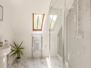 een witte badkamer met een douche en een wastafel bij South Wood Lodge in Slindon