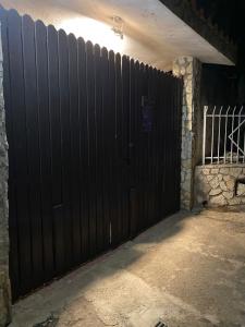 ein schwarzes Tor in einer Garage mit einer Steinmauer in der Unterkunft Dolce Vita casa vacanze in Carini