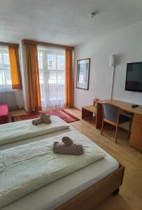 a bedroom with two beds and a desk and a television at Hotel Landhaus Zell am See in Zell am See