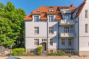 una gran casa blanca con techo naranja en Lion Apartments - Palermo Spacious Family Apartment 3 min walk from the beach, en Sopot