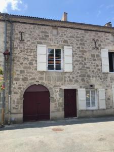 a stone building with two garage doors and a window at L'Horizon de Marianne in Montagnac-sur-Auvignon