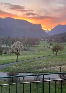 a sunset over a field with mountains in the background at LE NID DU BIRDIE, Giez, Proche du lac d’Annecy in Giez