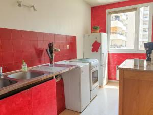 a red kitchen with a sink and a refrigerator at ZOLA T2 calme et équipé limitrophe de Lyon avec le métro à 3min in Villeurbanne