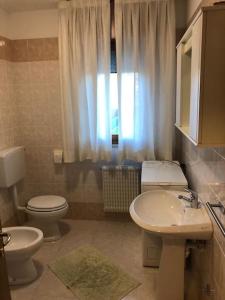 uma casa de banho com um lavatório, um WC e uma janela. em Confortevole Appartamento ad Aviano em Aviano