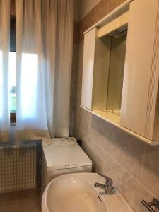 uma casa de banho com um lavatório, um WC e um espelho. em Confortevole Appartamento ad Aviano em Aviano
