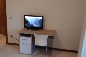 uma secretária de computador com uma televisão por cima em Confortevole Appartamento ad Aviano em Aviano