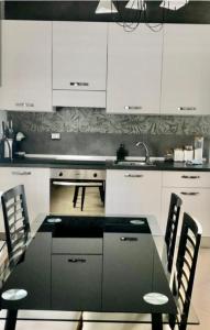 - une cuisine avec des placards blancs, une table et des chaises dans l'établissement Lovely Apartment Bergamo, à Bergame