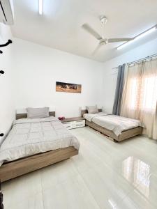 1 dormitorio con 2 camas y ventilador de techo en Hisn aljabal chalet, en Qurayyah