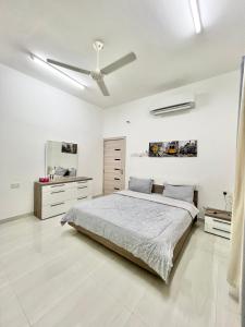 1 dormitorio blanco con 1 cama y ventilador de techo en Hisn aljabal chalet, en Qurayyah