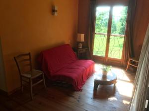 a bedroom with a red bed and a window at Maison Bélinaire - Au coeur de la nature in Cazeneuve-Montaut