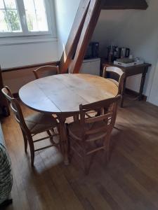 una mesa de madera y sillas en una habitación en Le Plantard, en Ruaudin