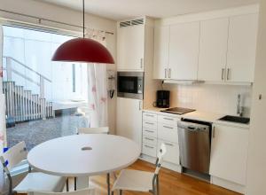 cocina blanca con mesa blanca y sillas en Lovely holiday apartment in Mellbystrand en Mellbystrand