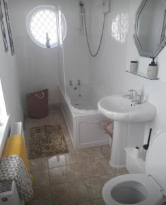 Baño blanco con lavabo y aseo en Porthcawl cottage, en Newton