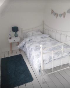 białe łóżko w białej sypialni z dywanem w obiekcie Porthcawl cottage w mieście Newton