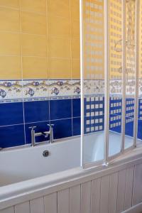 ein Badezimmer mit einer Badewanne mit blauen und gelben Fliesen in der Unterkunft Elegant Guest House FREE WiFi & Parking in Killingbeck