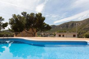 une grande piscine bleue en face d'une montagne dans l'établissement Piscina, parking y relax!, à Castelldefels