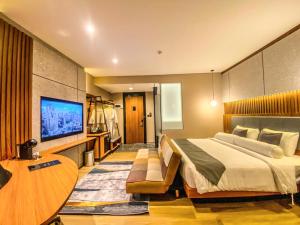 a hotel room with a large bed and a flat screen tv at Nata Azana Hotel Solo in Solo