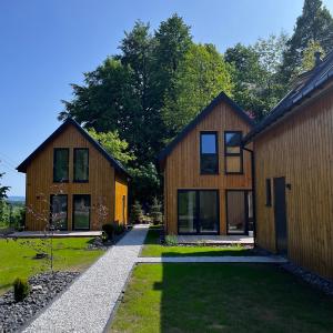 dwa drewniane domy z trawnikiem i drzewami w obiekcie Chatki Między Górami w mieście Sosnówka