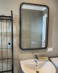 La salle de bains est pourvue d'un lavabo et d'un grand miroir. dans l'établissement Sara blue apartment, à Tirana