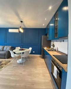 - une cuisine avec des murs bleus, une table et des chaises dans l'établissement Sara blue apartment, à Tirana