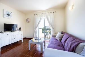 ein Wohnzimmer mit einem Sofa und einem TV in der Unterkunft Quinta do Paiva - Two Bedroom Apartment Olhos de Agua in Albufeira