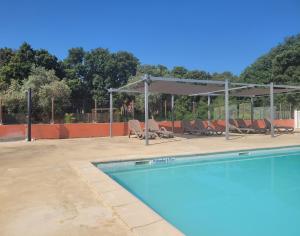 - une piscine avec des chaises et un auvent dans l'établissement Hôtel Domaine le Milos, à Castries