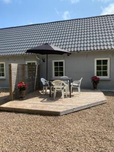 a patio with a table and chairs and an umbrella at Apt17 - Guest house just outside of Billund - rural and quiet surroundings in Billund