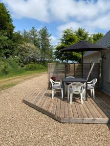 um deque de madeira com uma mesa, cadeiras e um guarda-sol em Apt17 - Guest house just outside of Billund - rural and quiet surroundings em Billund