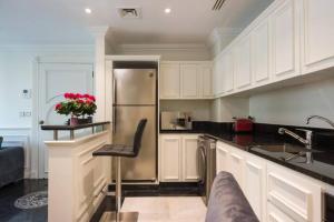 a kitchen with white cabinets and a stainless steel refrigerator at Versace Tower Luxury Suites - Downtown in Beirut