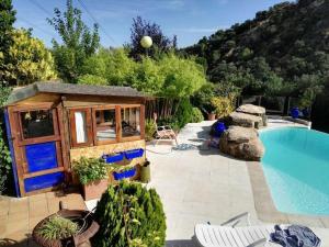 een tiny house naast een zwembad met een gebouw bij Casa con vistas increíbles, piscina Infinity y jardín con rincones preciosos in Las Rozas de Madrid